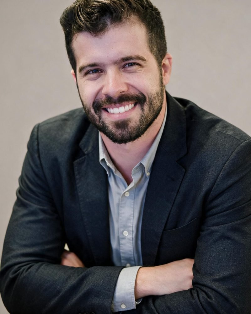 Glauco Kozlowski, fundador da Raio, sorrindo, de blazer escuro.